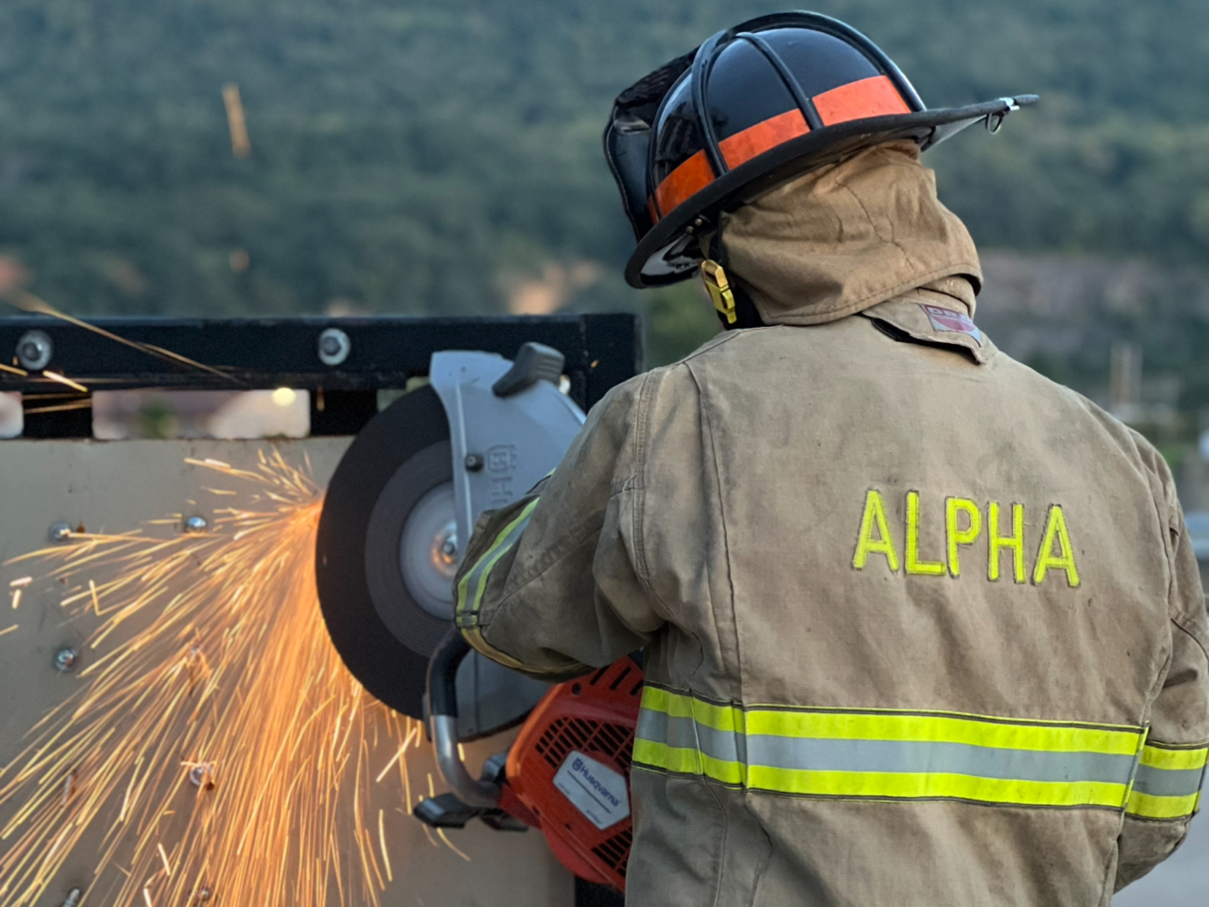 Person in firefighter coat cutting through metal