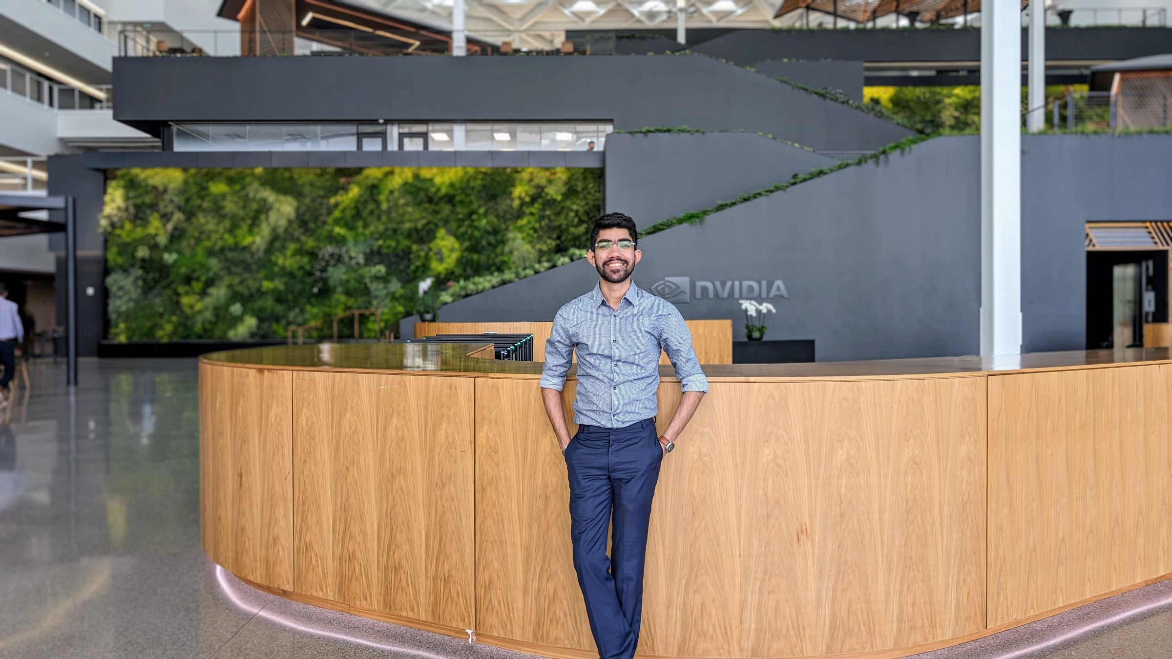 person with dark facial hair and glasses in office building