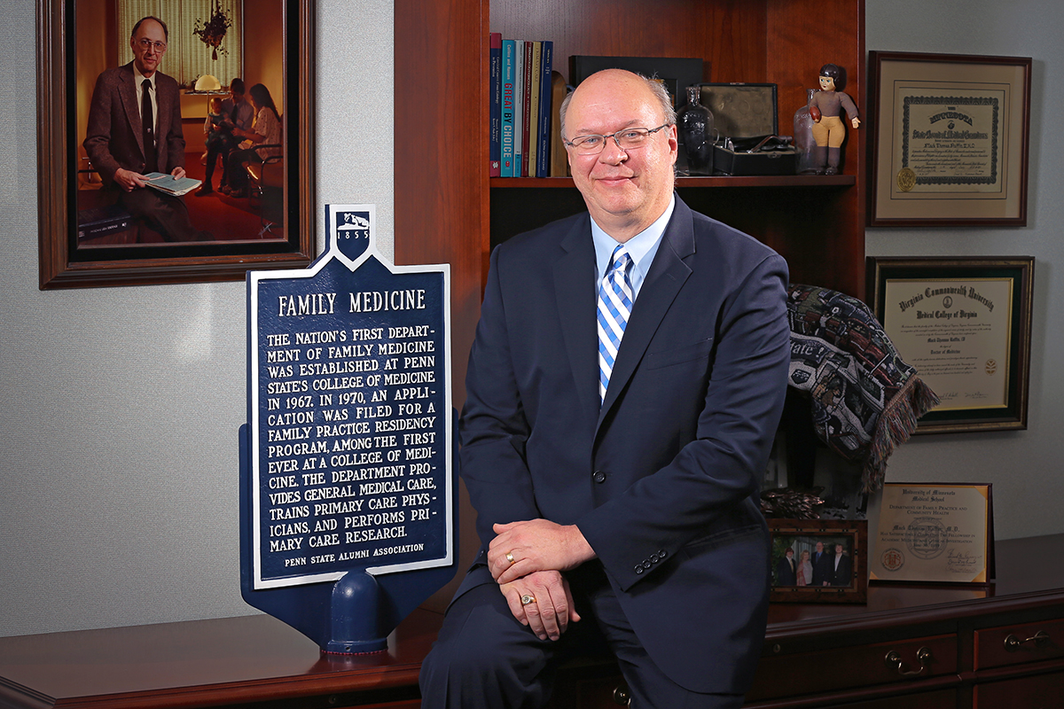 Dr. Mack Ruffin IV sits for a professional portrait next to an historical marker about the nation's first Department of Family Medicine being established at Penn State College of Medicine in 1967.