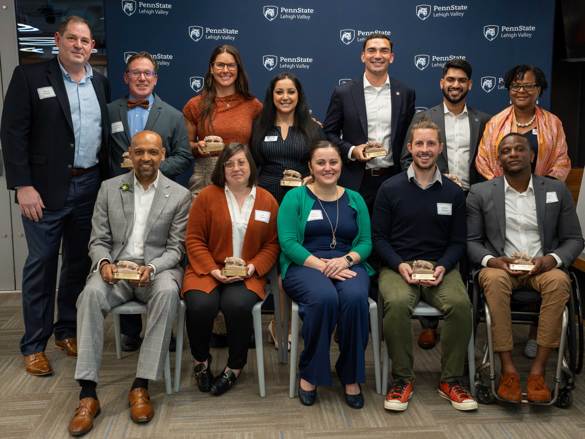 a group of Penn State Lehigh Valley award recipients smiling in front of a blue backdrop