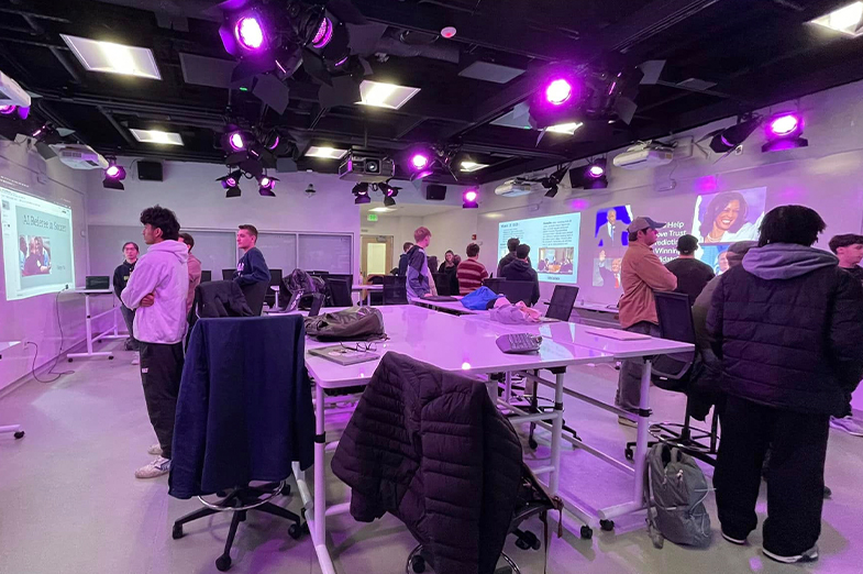 Students standing a looking at screens in a technology classroom