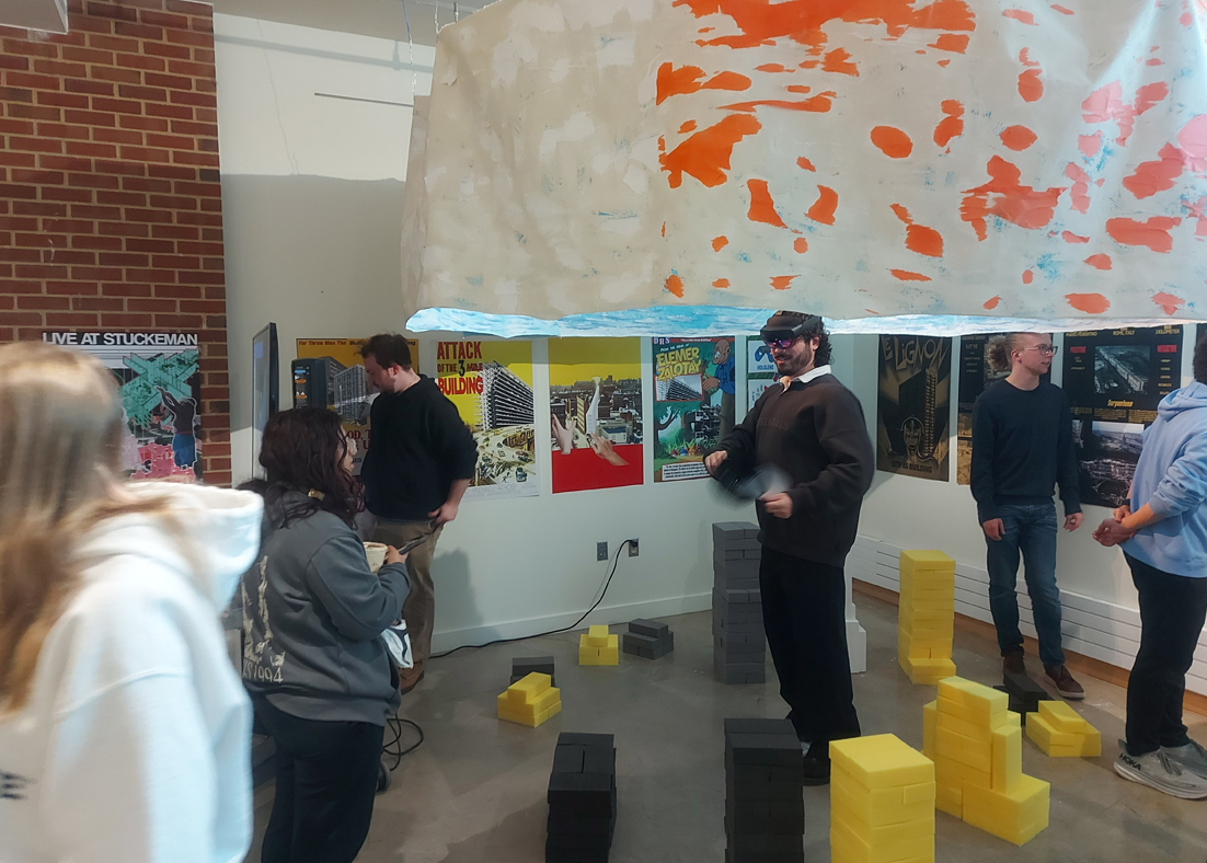 A group of students in an art gallery exploring installations including one student with a VR headset on. 