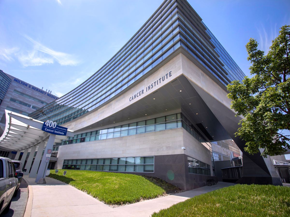 An exterior photo of Penn State Cancer Institute, with plants and bushes in the foreground.