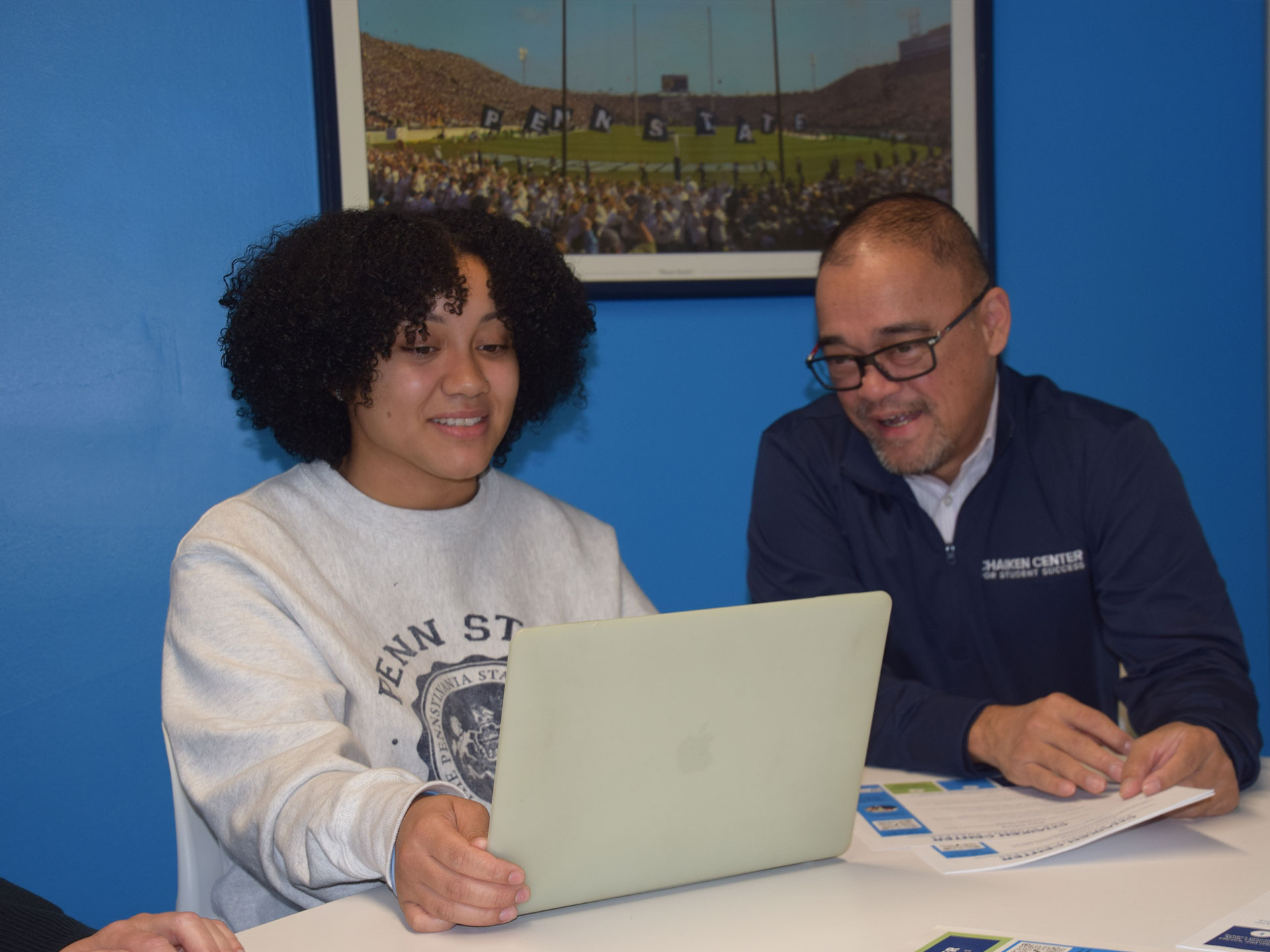 Student and staff member looking at laptop computer