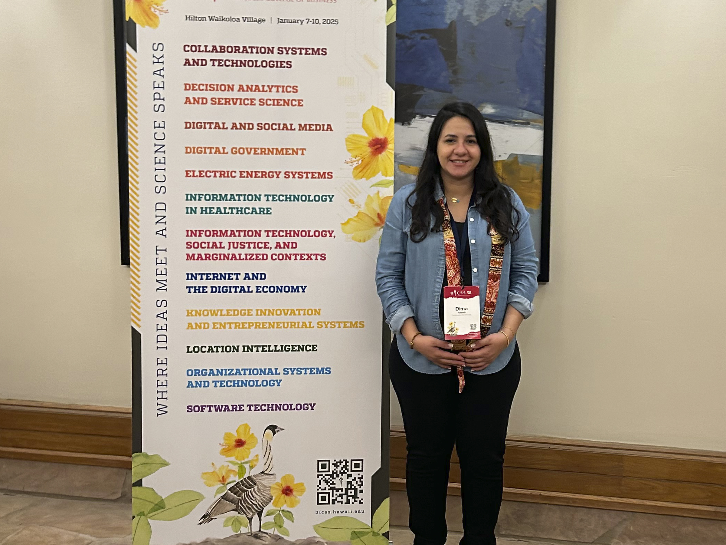 Dima Rabadi poses next to an HICSS Conference sign