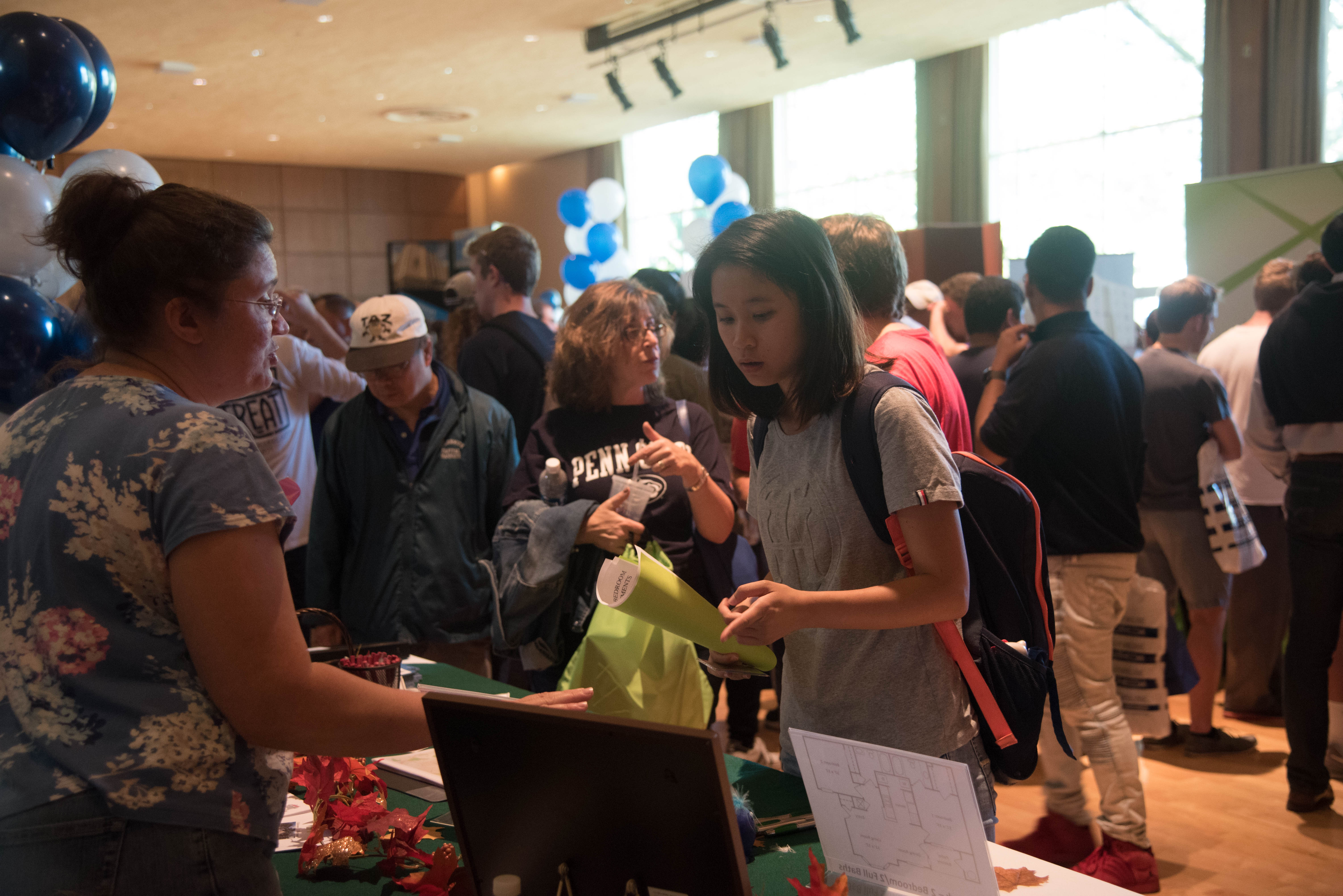 A student reading information at a table during a housing fair.