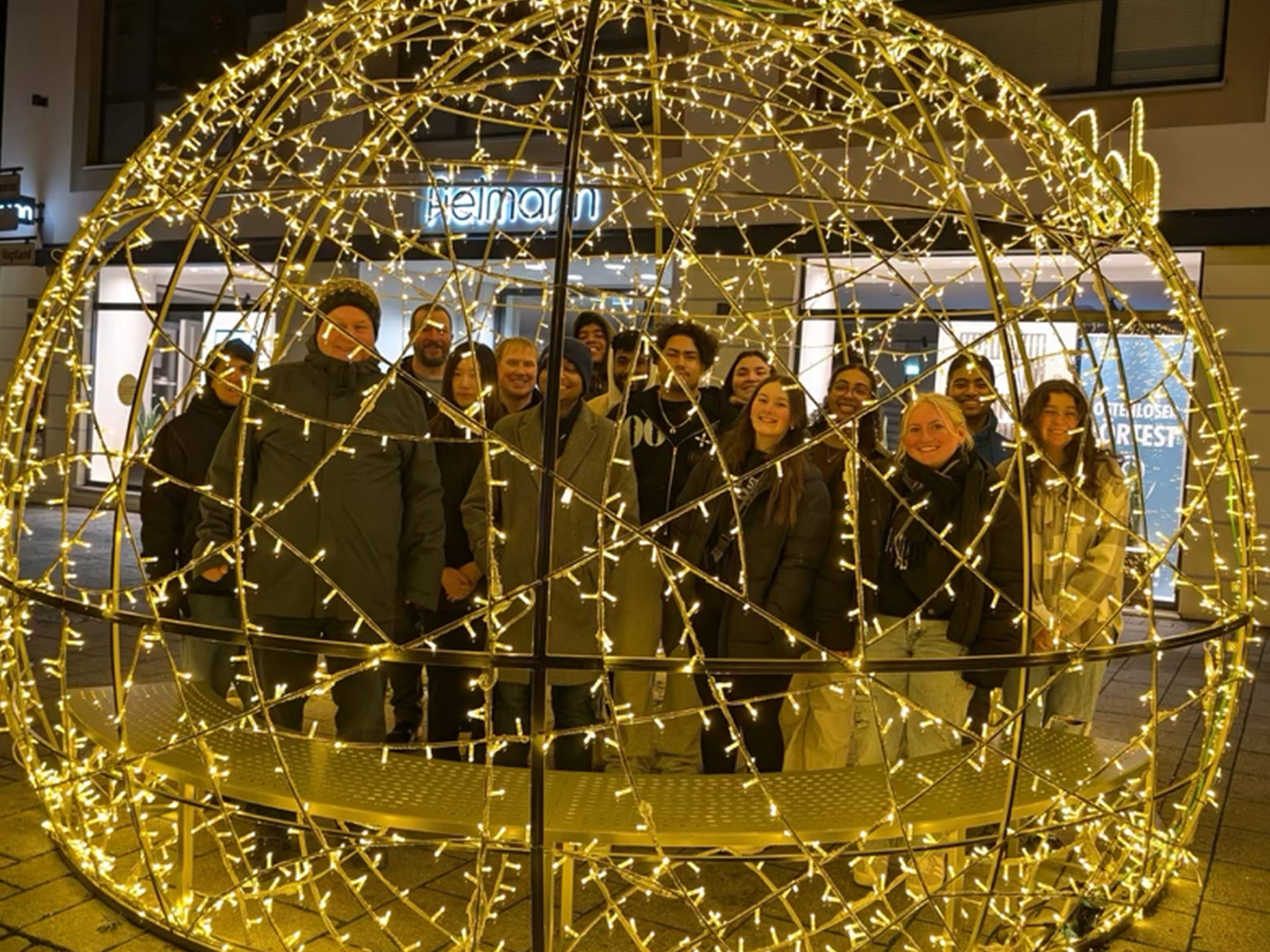 Students standing behind circular structure with twinkle light