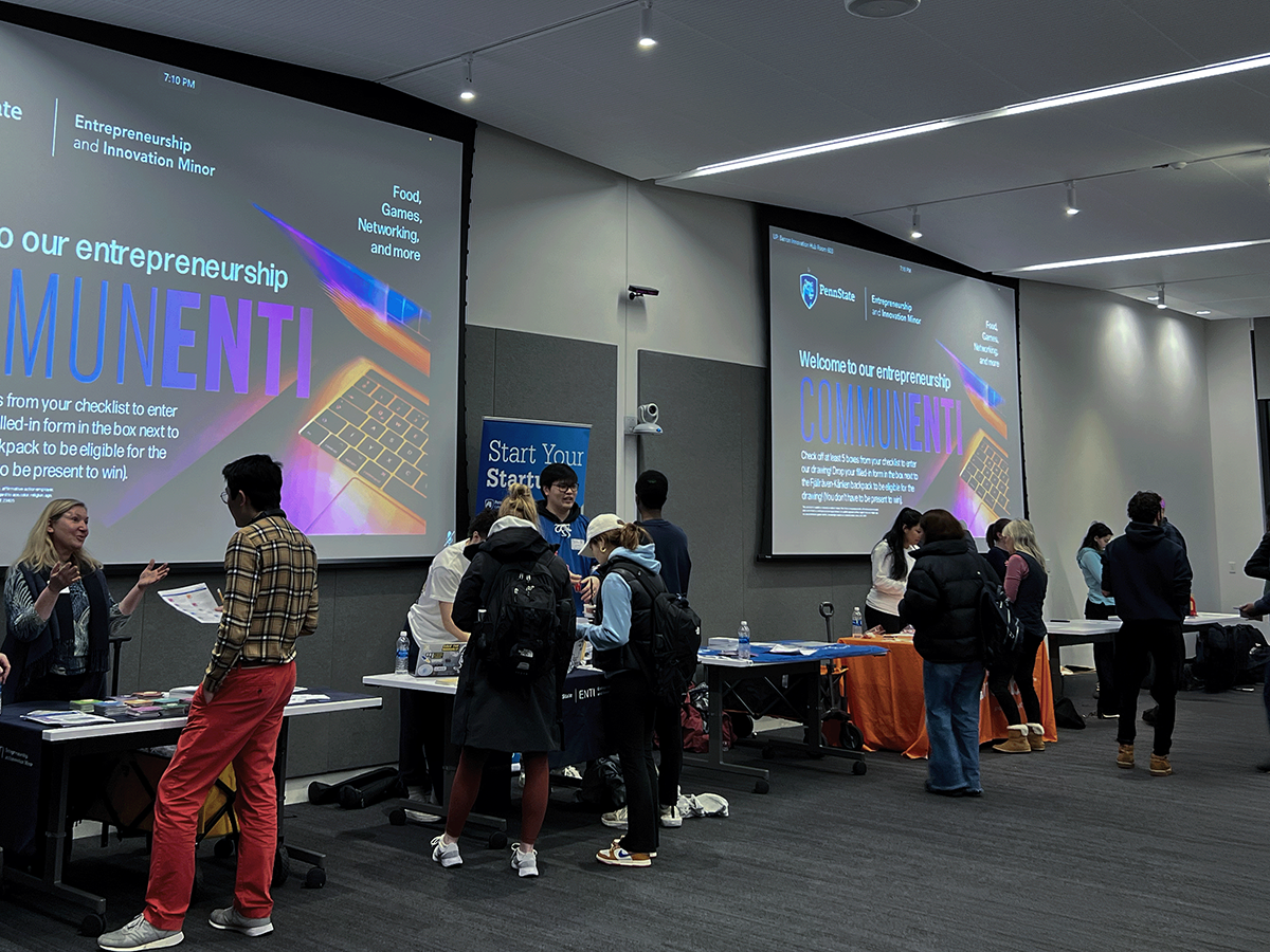 Students and staff mingle in front of tables and large screens saying "CommunENTI"