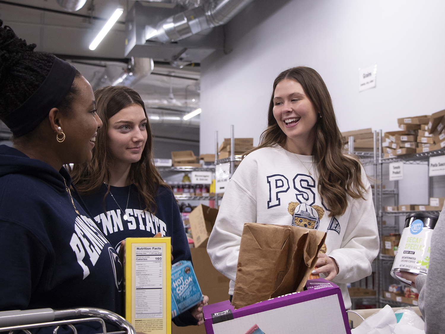 Four students standing around a bin of food donations helping sort them