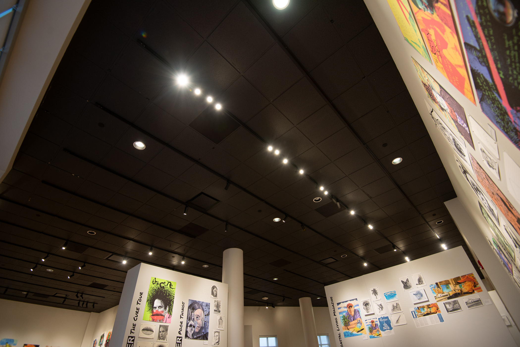 A view from below of lighting on the ceiling of a gallery