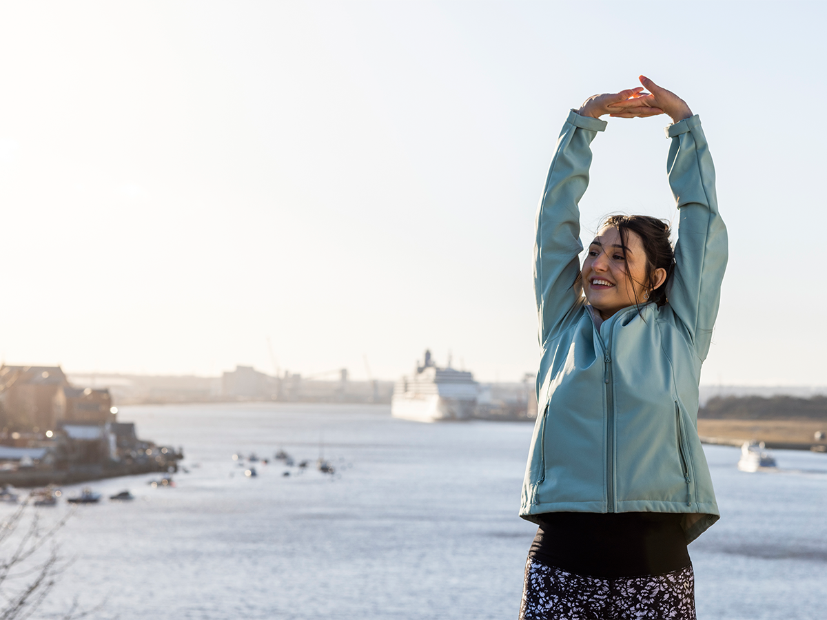 Woman in workout clothes stretching in front of harbor