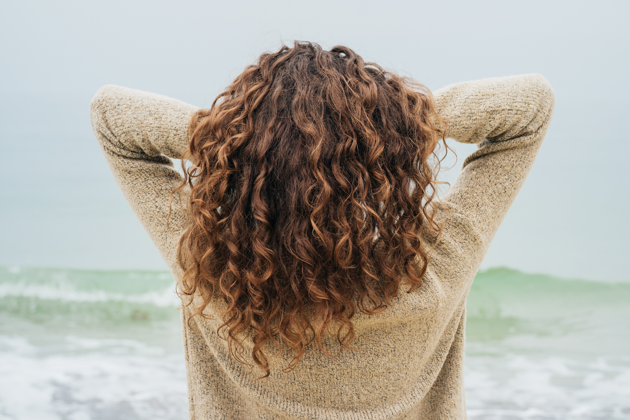 A woman with curly brown hair facing the sea