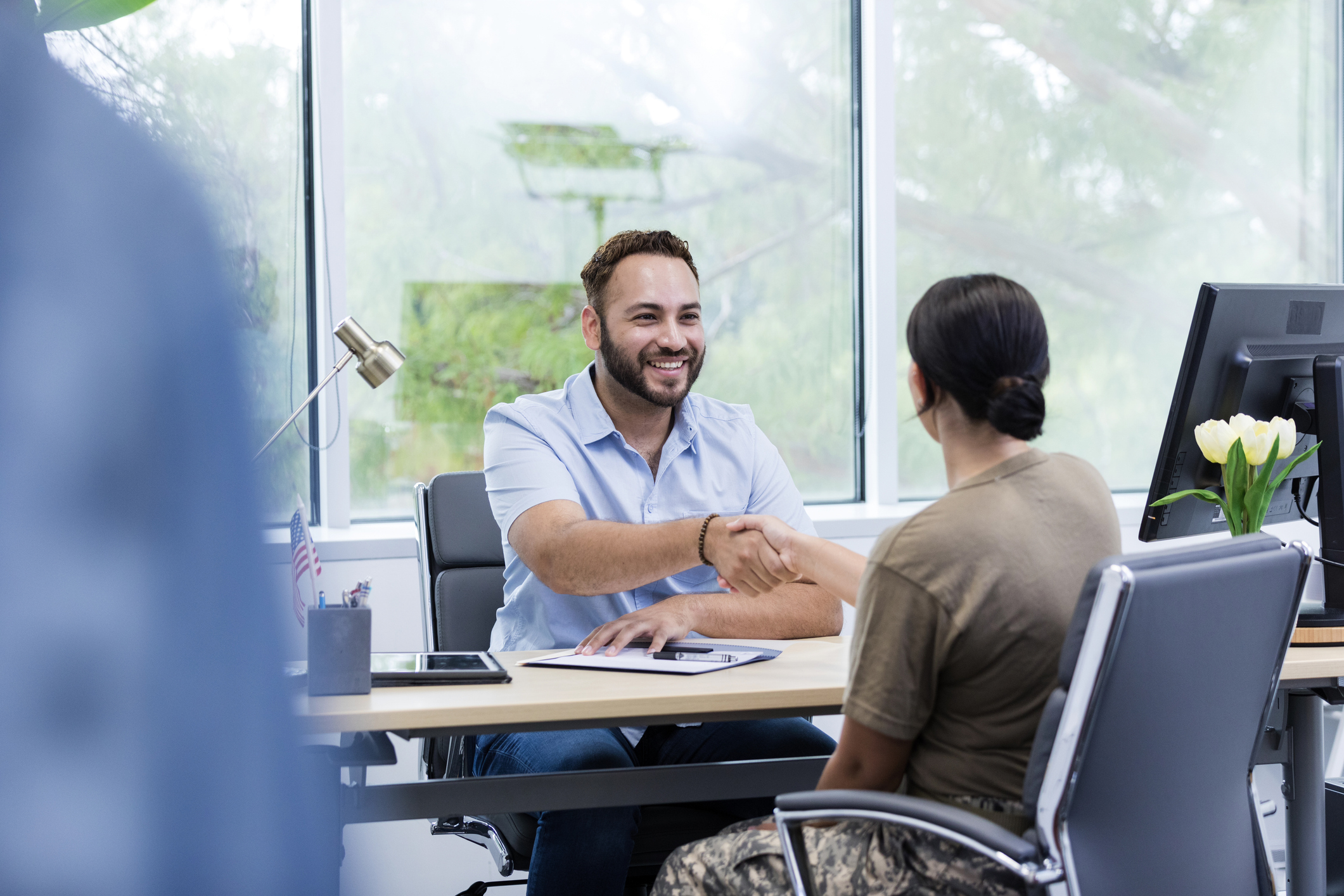 A soldier meets with the job recruiter to talk about employment options at a desk.