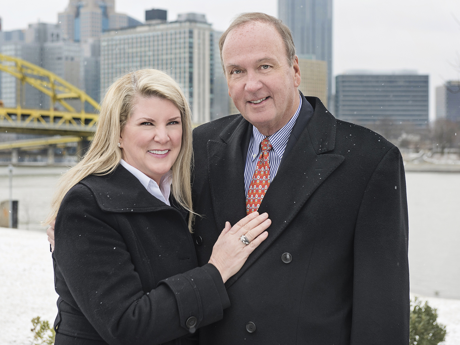 A photo of Kristen and Mike Farrell with the Pittsburgh skyline in the background.