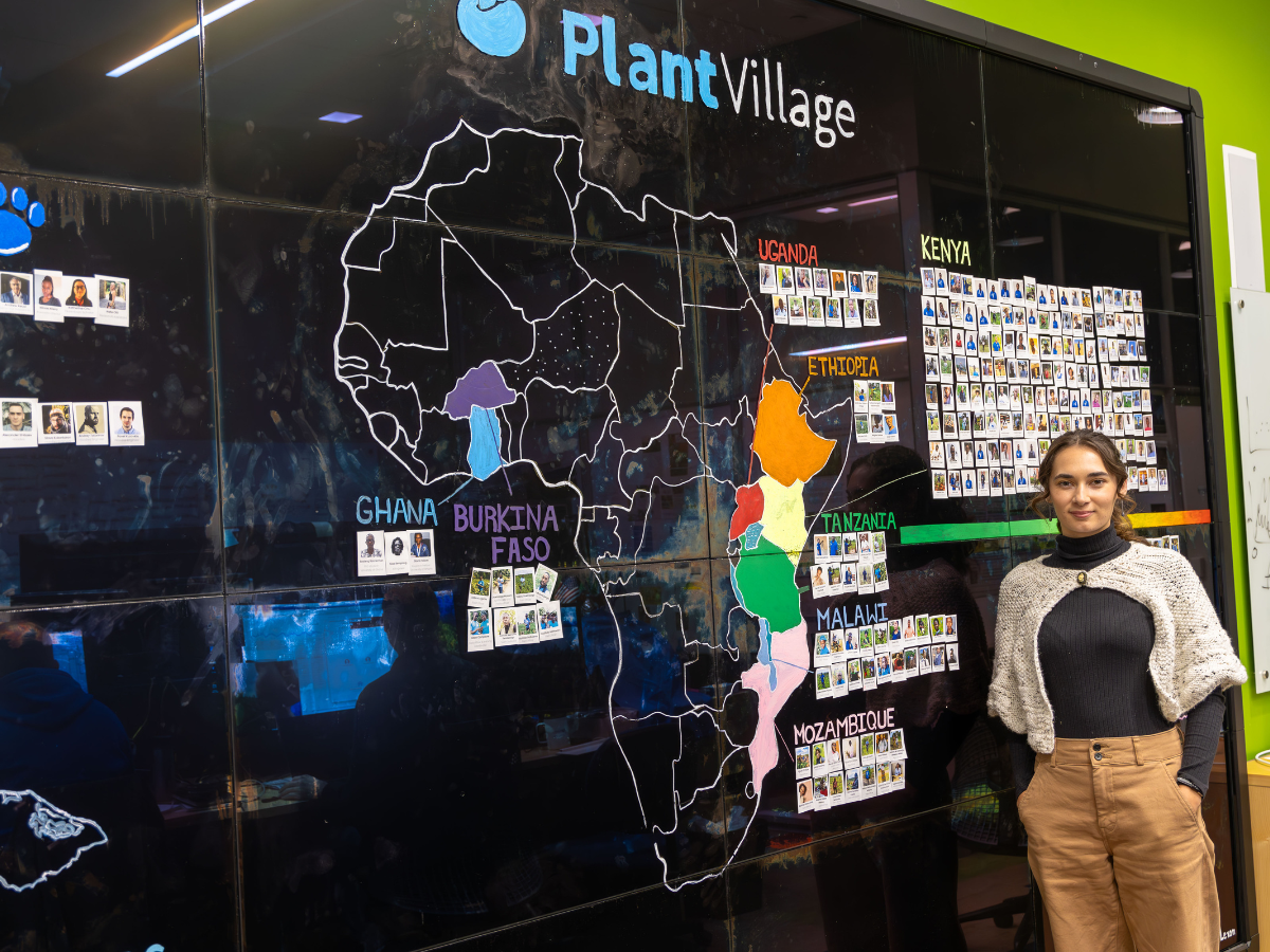 Annalyse stands in front of a map of Africa that notes the different countries where PlantVillage is active