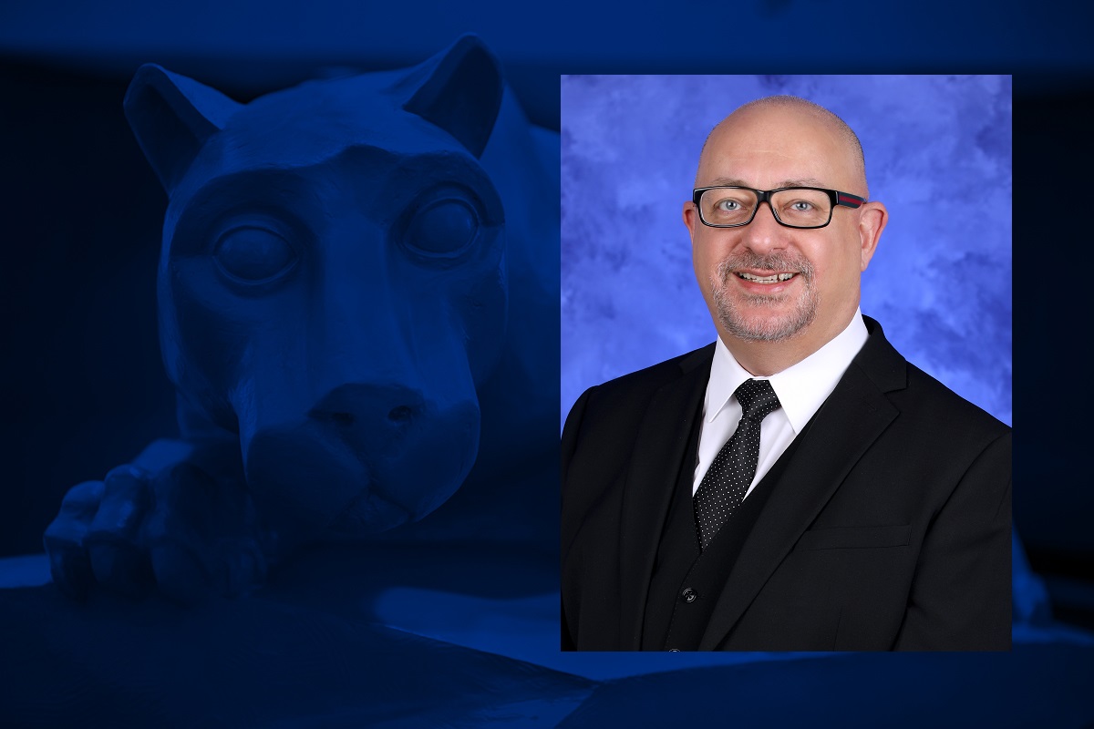 A headshot of a man wearing glasses is overlaid on a blue graphic with a statue of a lion mascot