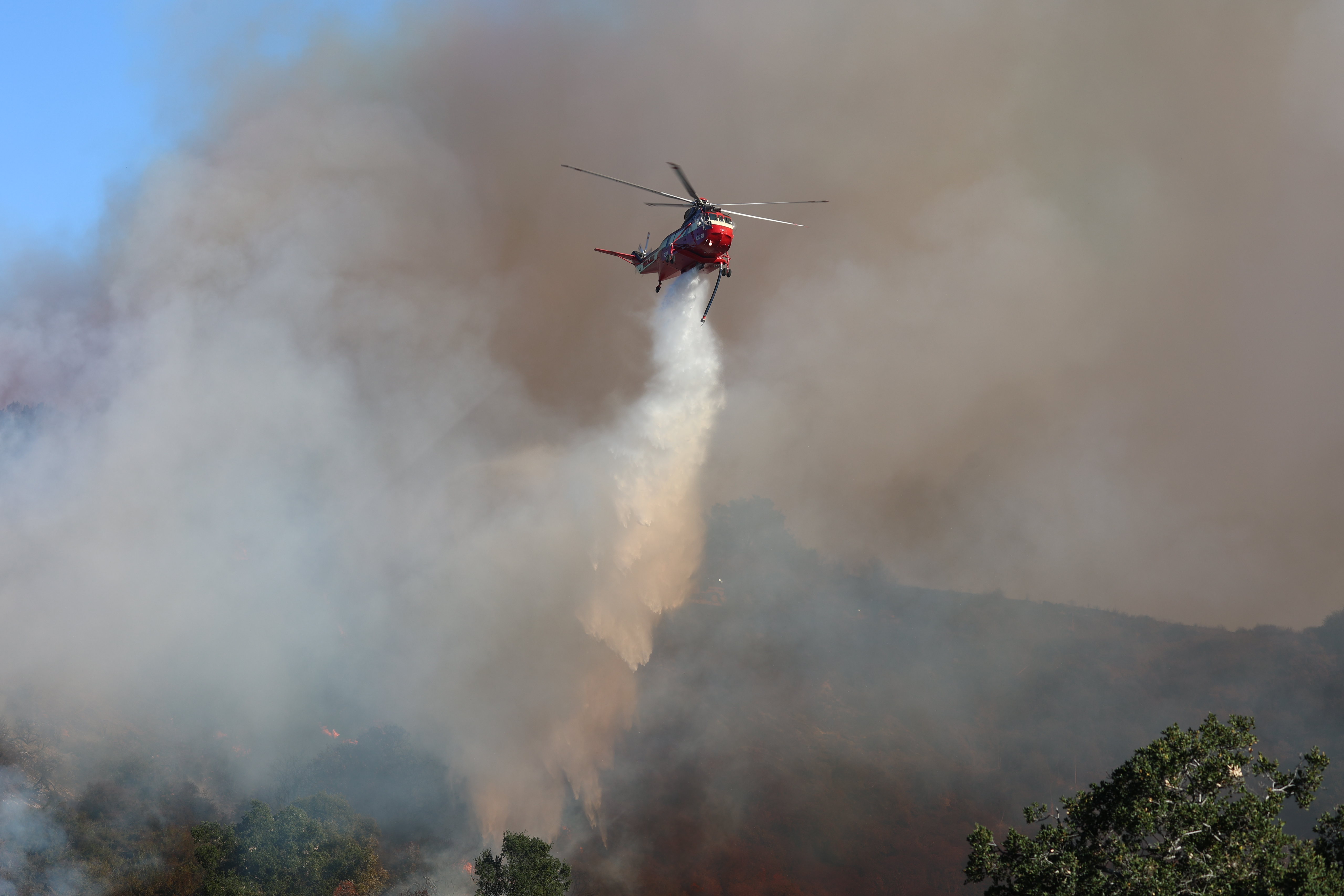 A helicopter drops water on a wildfire in Los Angeles in January 2025.