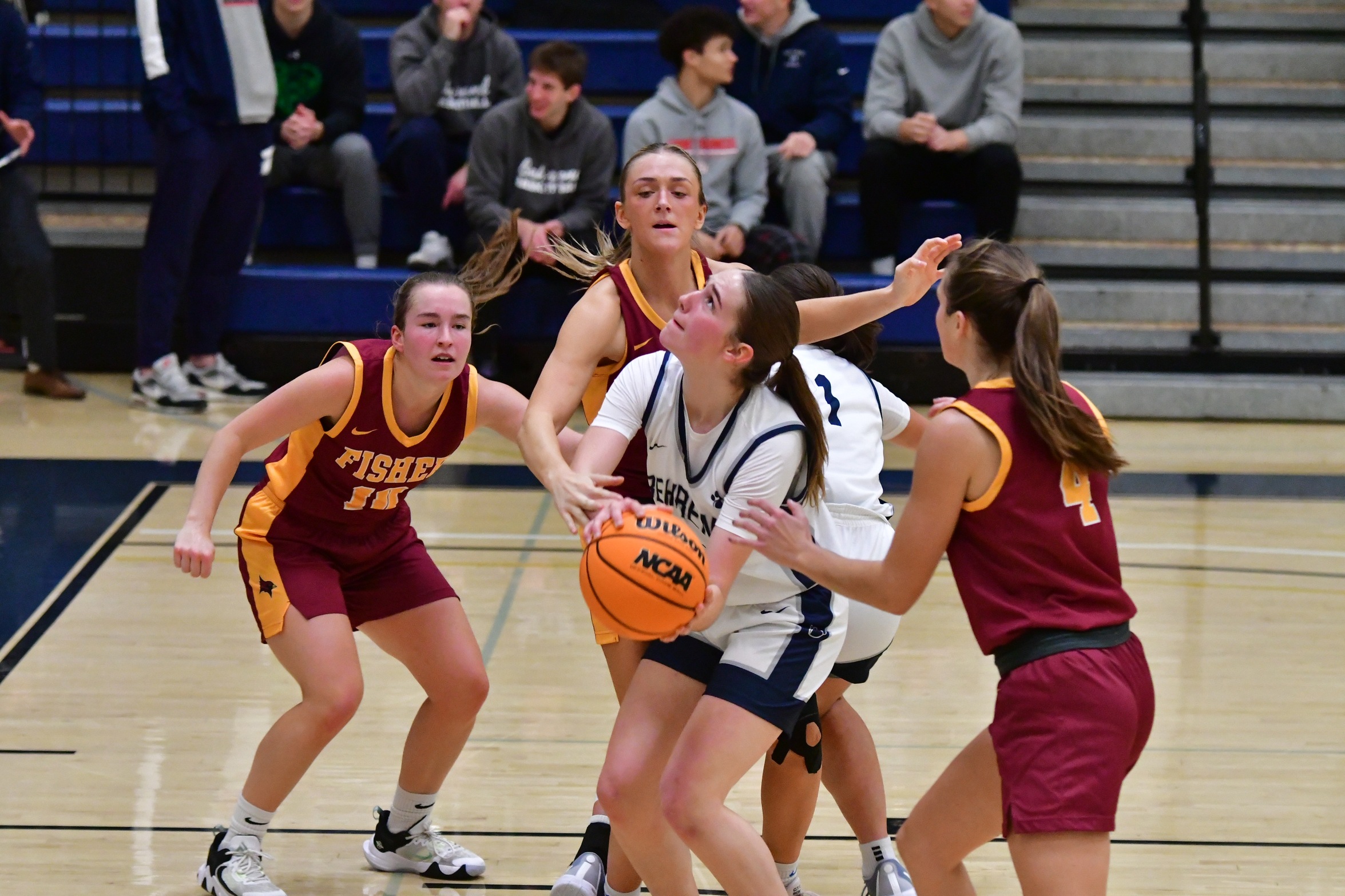 A Penn State Behrend basketball player prepares to shoot while being guarded by three opponents.