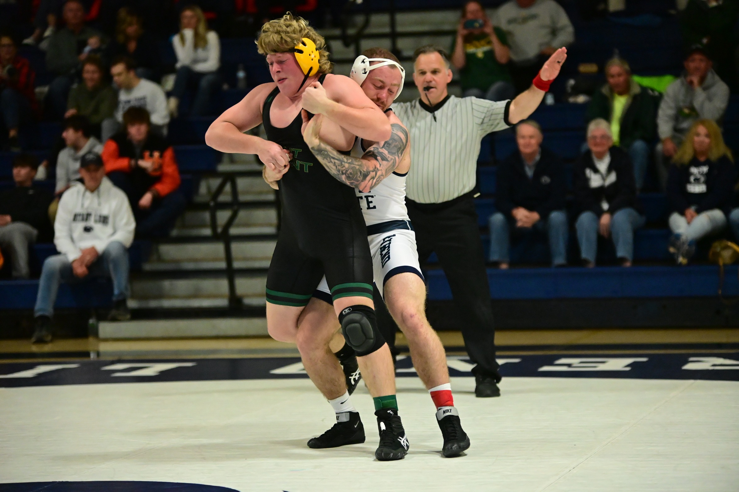 A Penn State Behrend wrestler grabs an opponent from  behind while standing.