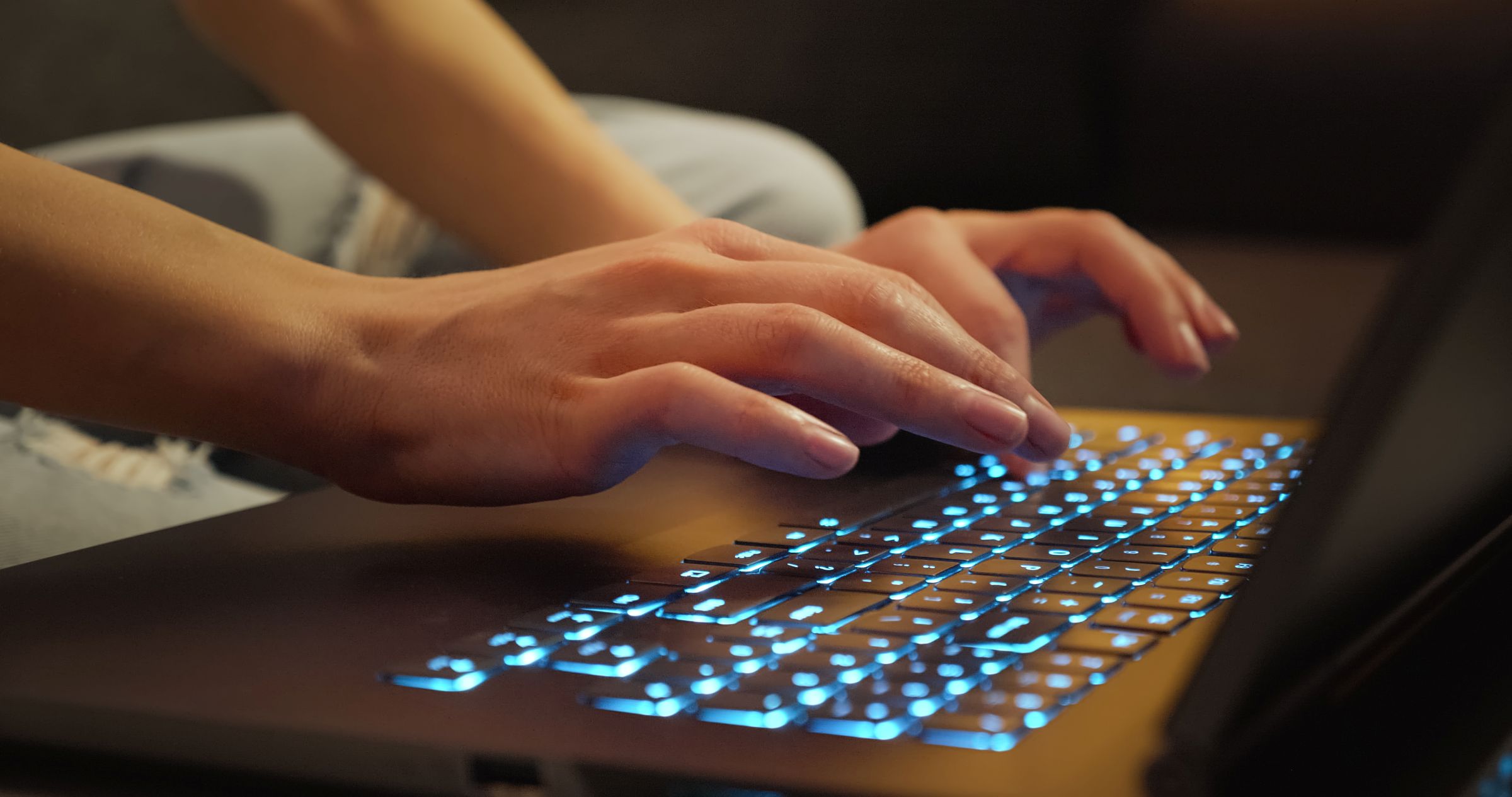 fingers hover over lighted laptop keyboard