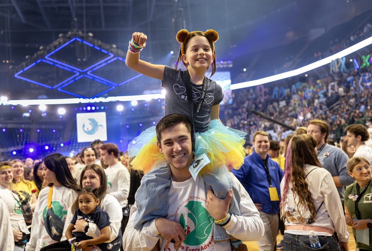 A child in a tutu sits on the shoulders of a college student at THON, celebrating.