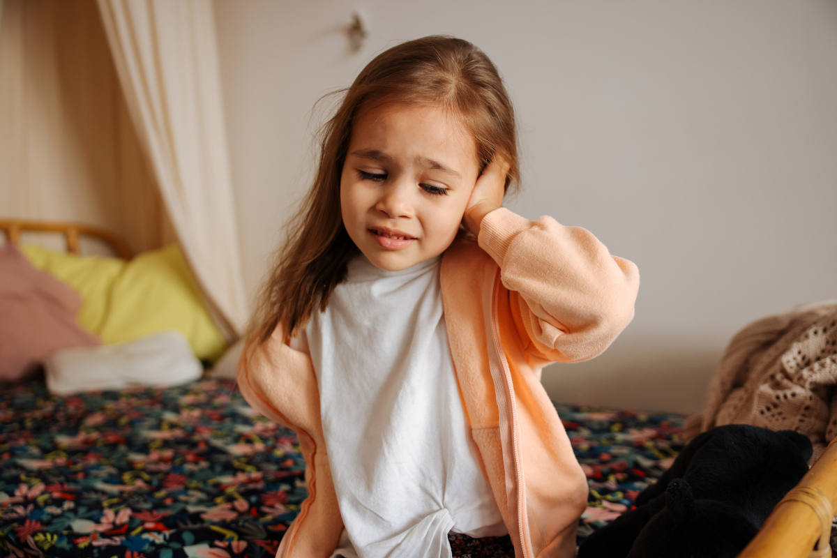 A young girl with an earache holds her ear.