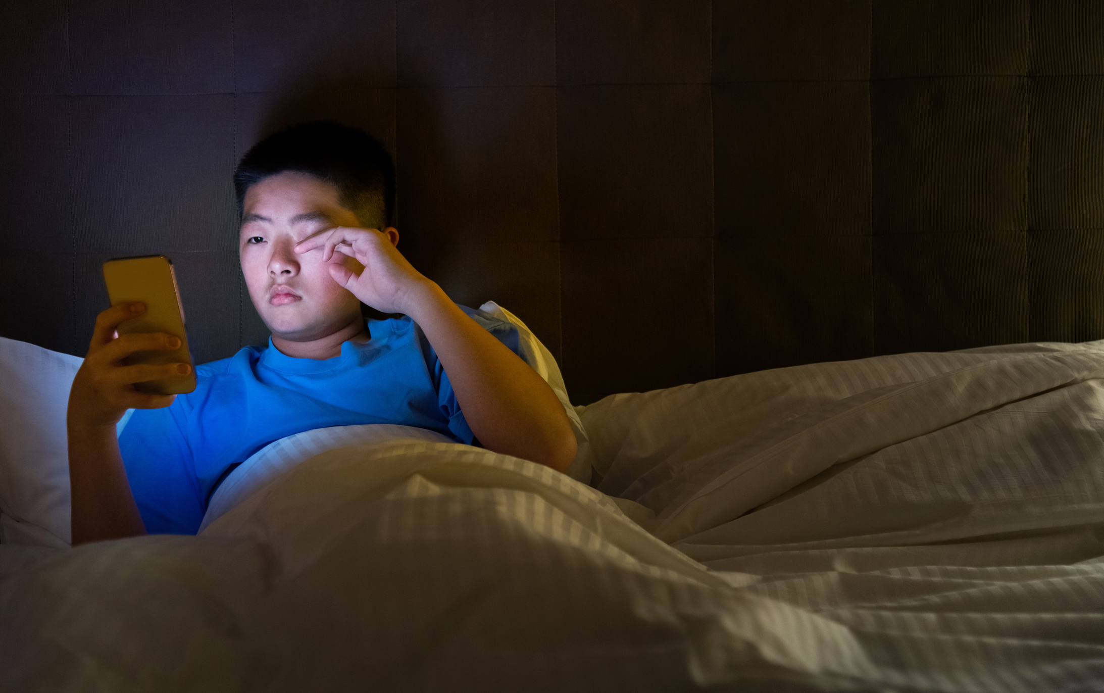 teenager in bed using mobile phone