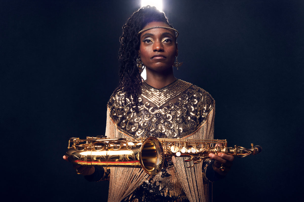 A Black woman holds a saxophone like an offering.