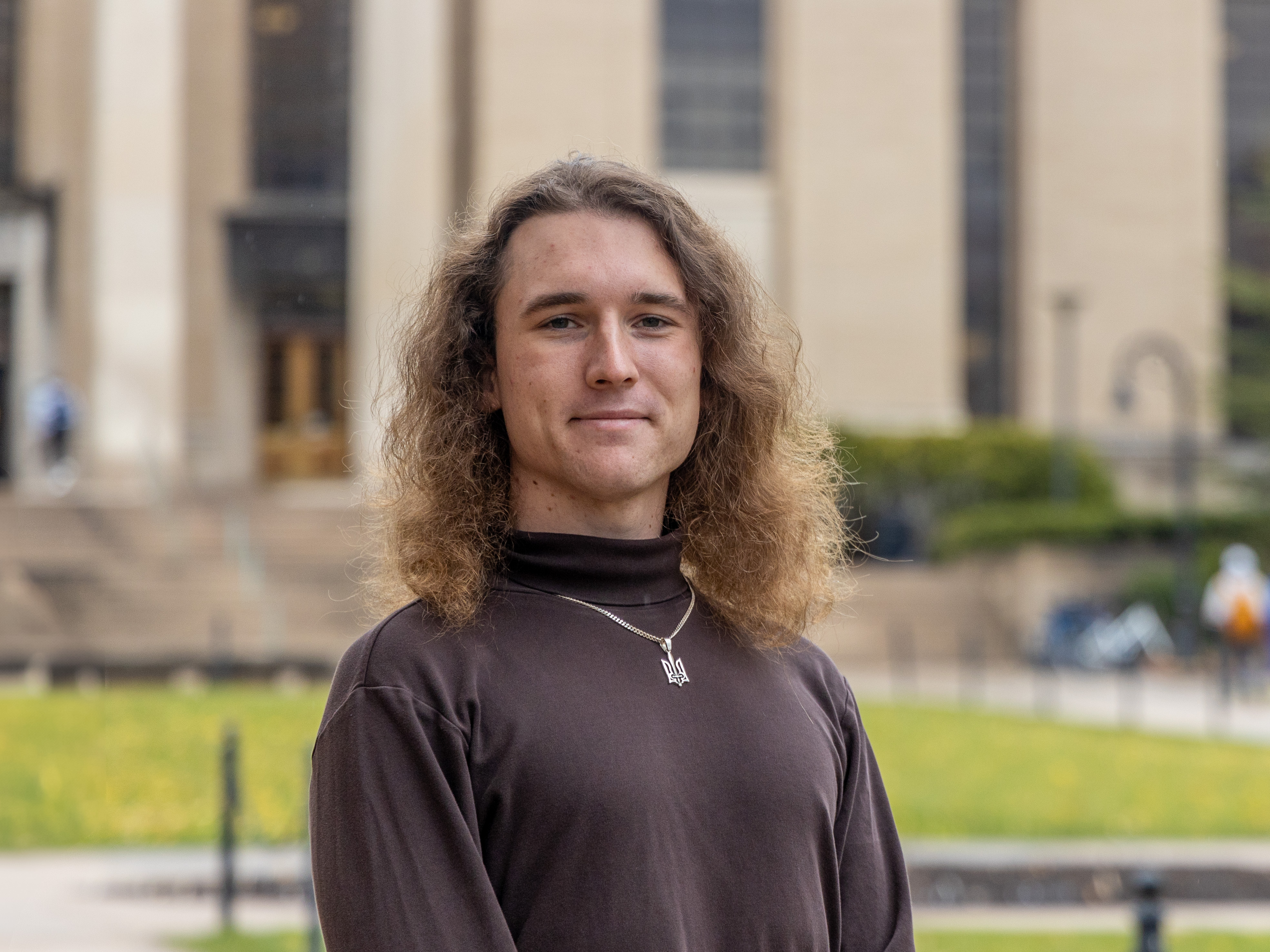 Igor Latsanych stands on Pattee Mall with Pattee Library and Paterno Library behind him.