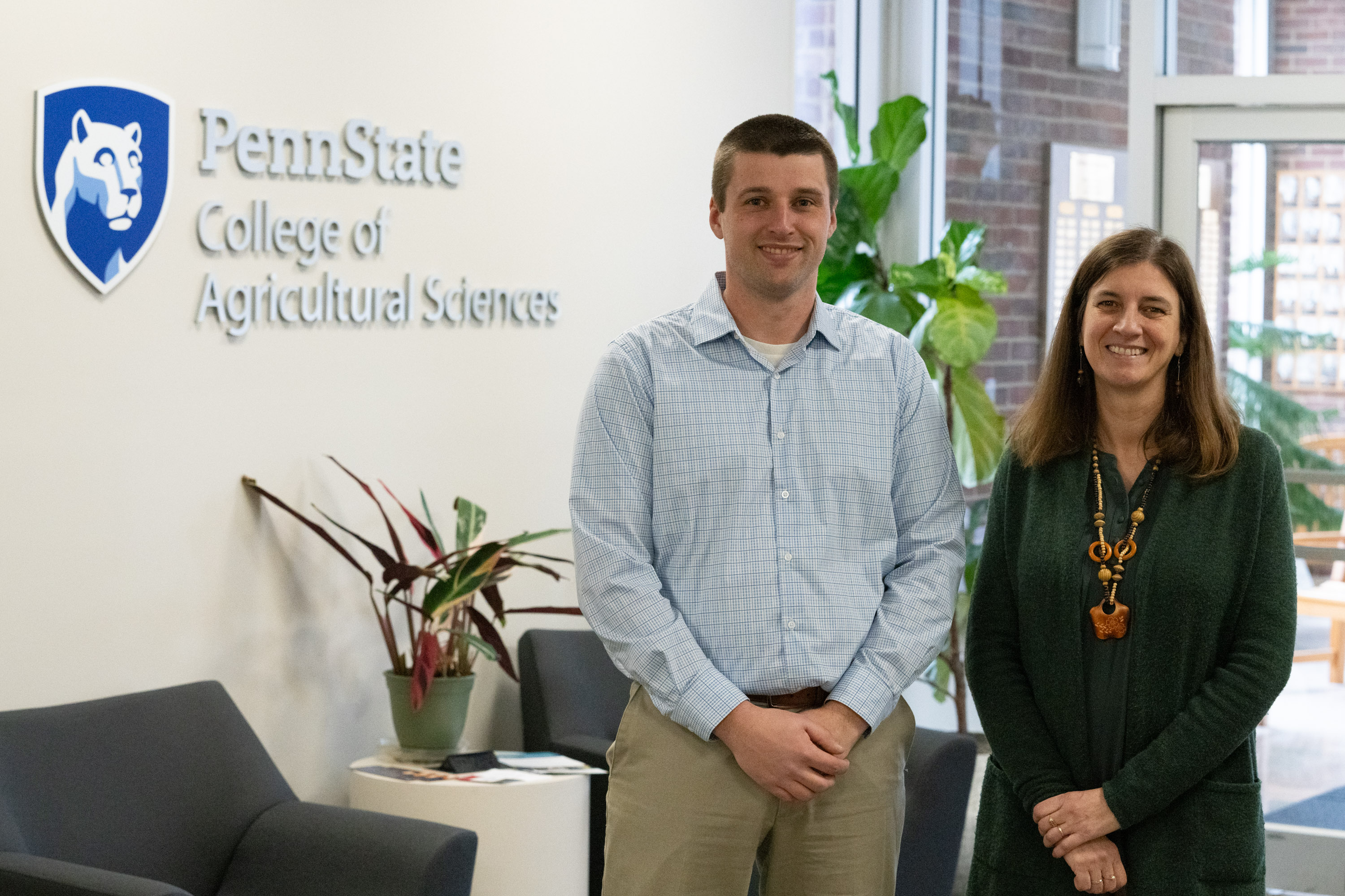 Two people stand in front of a wall that reads "Penn State College of Agricultural Sciences"