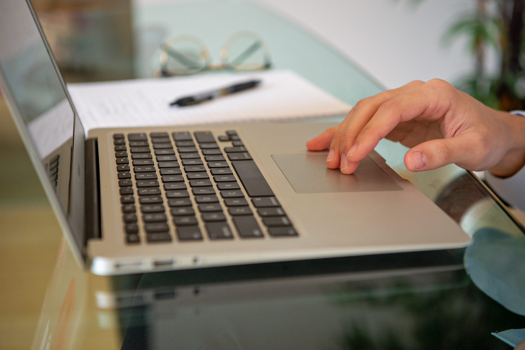 A computer laptop open for work with a hand resting on the track pad