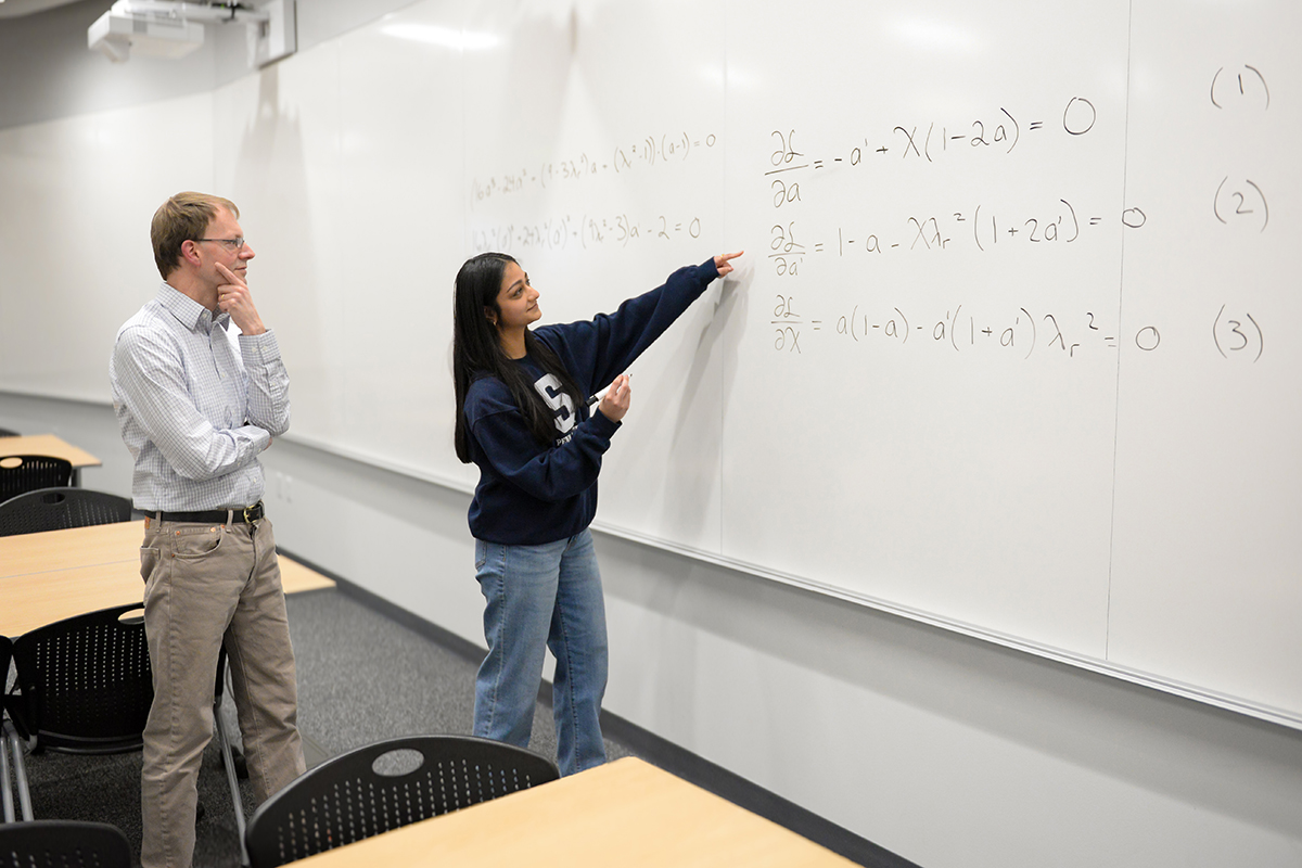 Two people in front of a white board