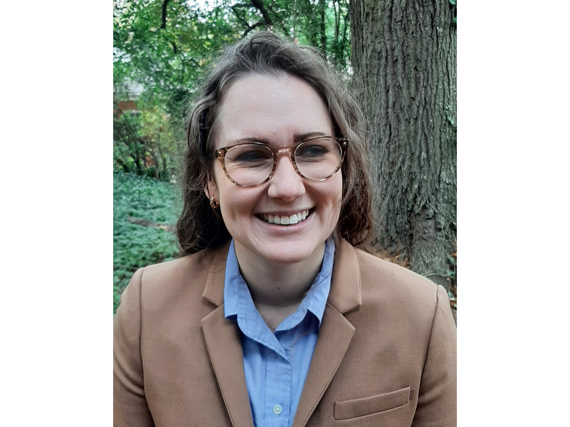 Tracee Saunders, a woman with brown, shoulder-length hair with glasses and a tan blazer.