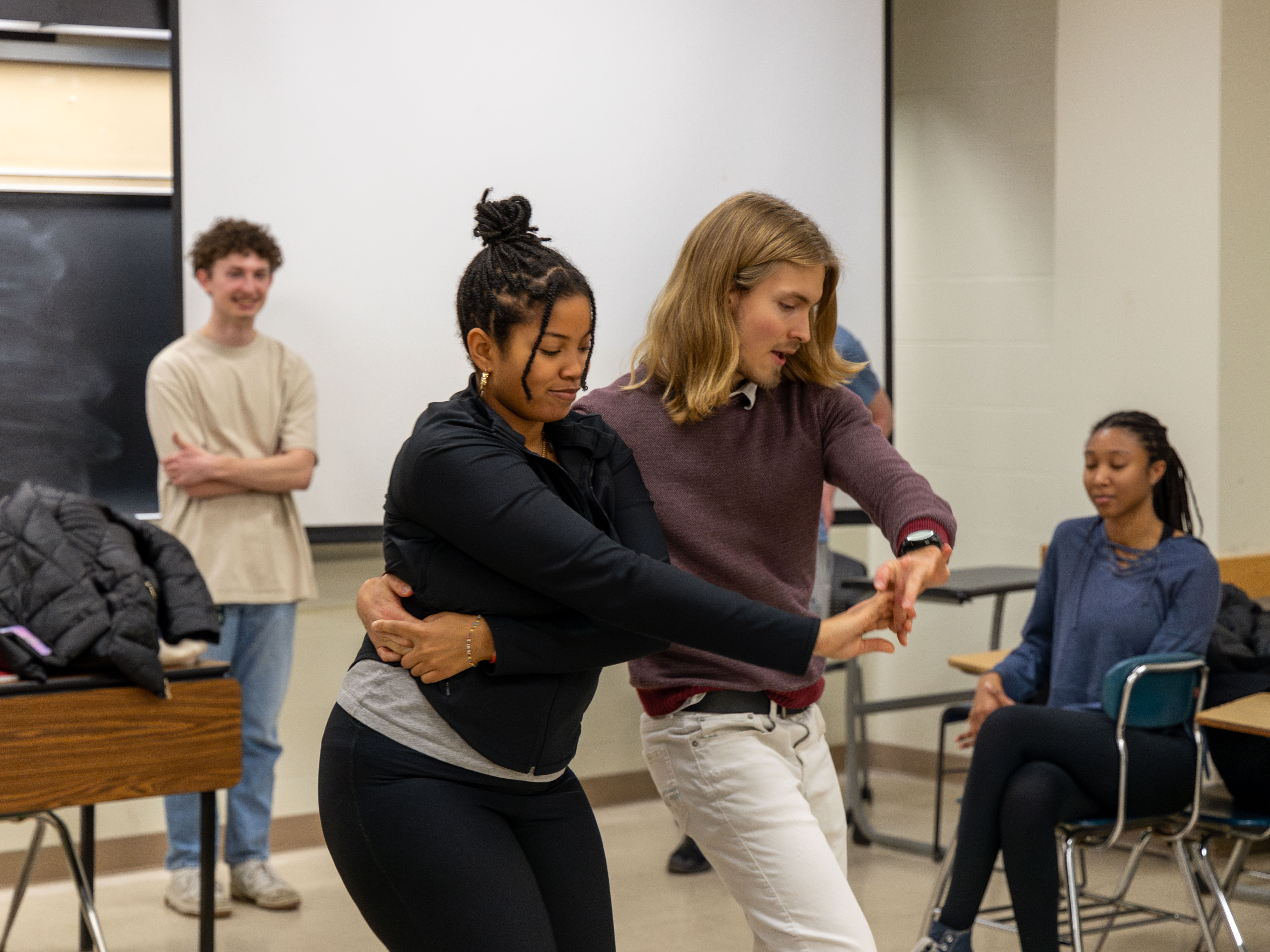 Elana Laing (front left) and Victor Frolenko (front right) demonstrate the merengue dance style during their SPAN 197 course in front of three other students in a classroom.