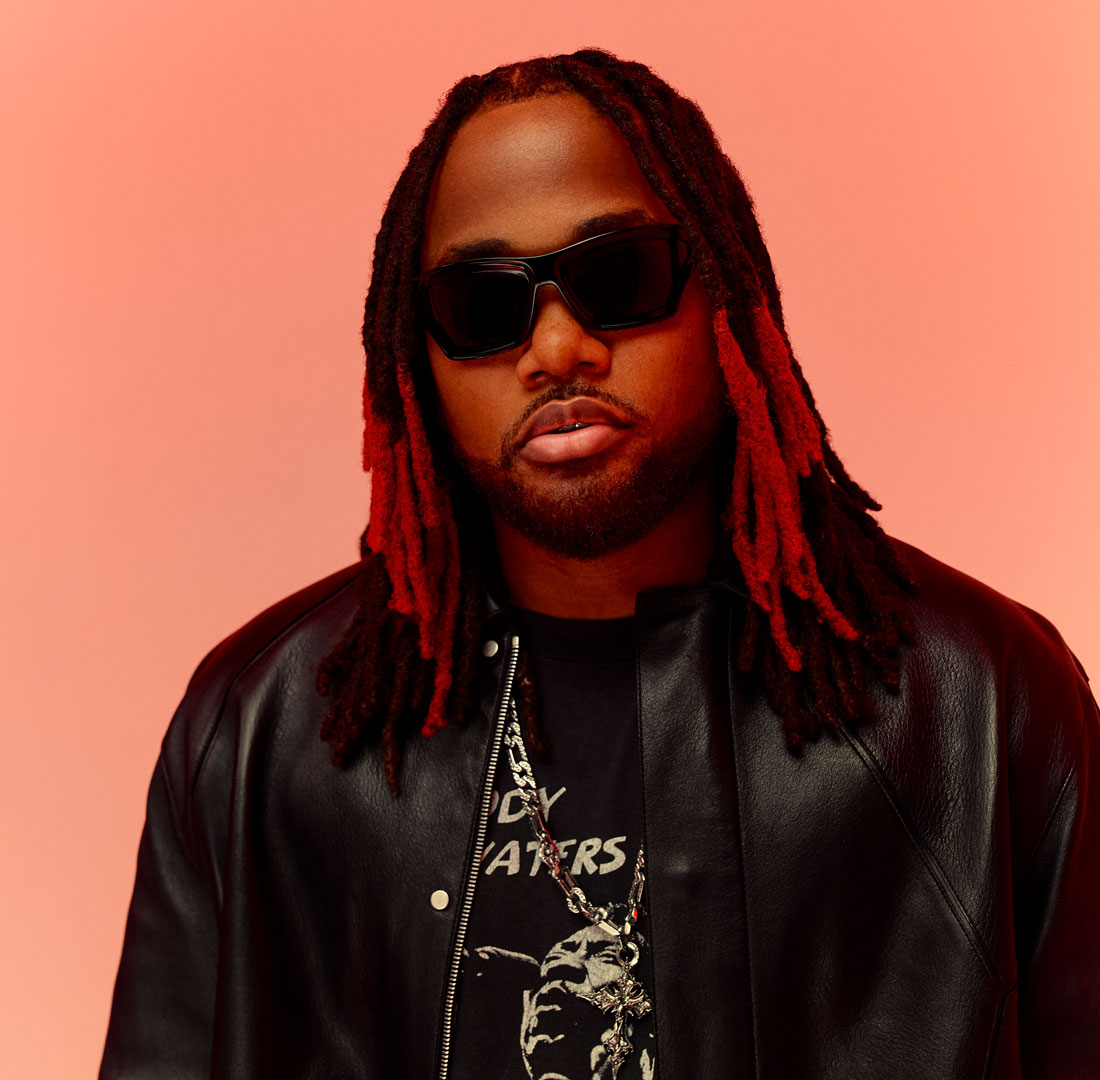 A Black man with dreadlocks wears sunglasses.