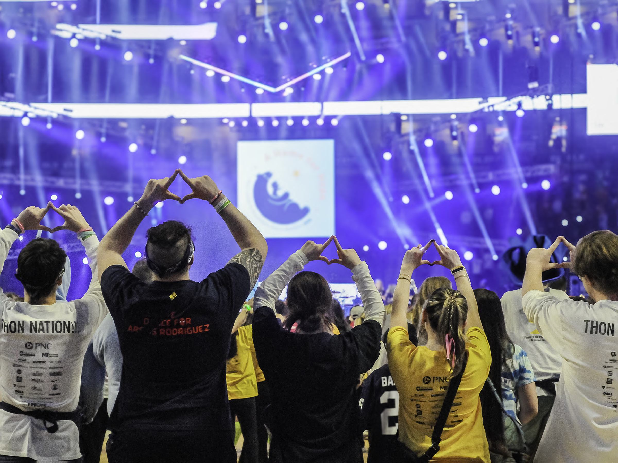 Scranton THON dancers face the stage and make the Four Diamonds symbol with their hands