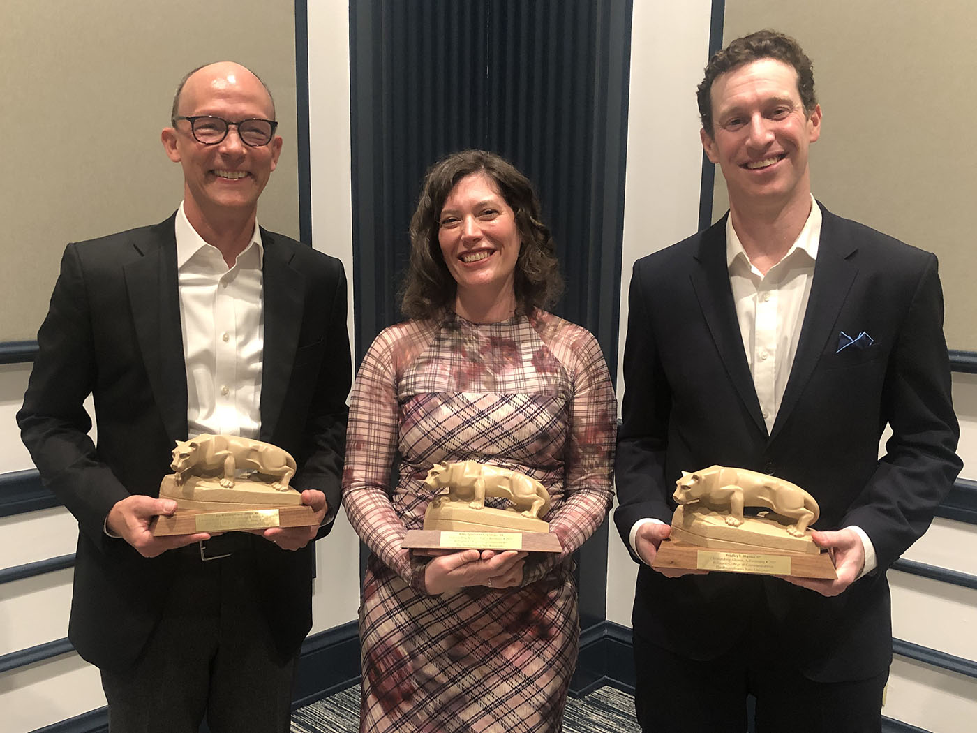 Three people holding Nittany Lion statuettes