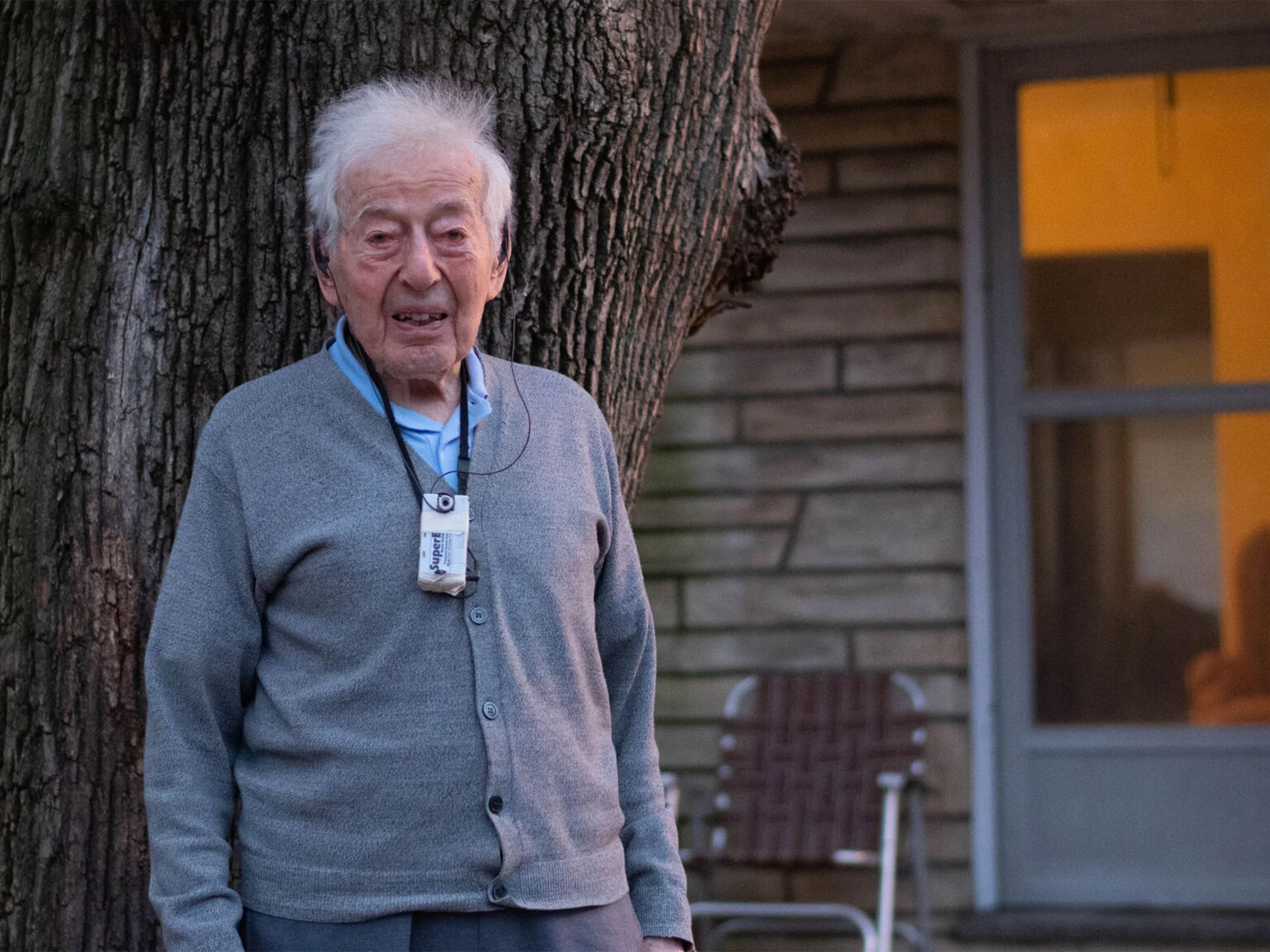 An individual poses in front of a house in the evening. 