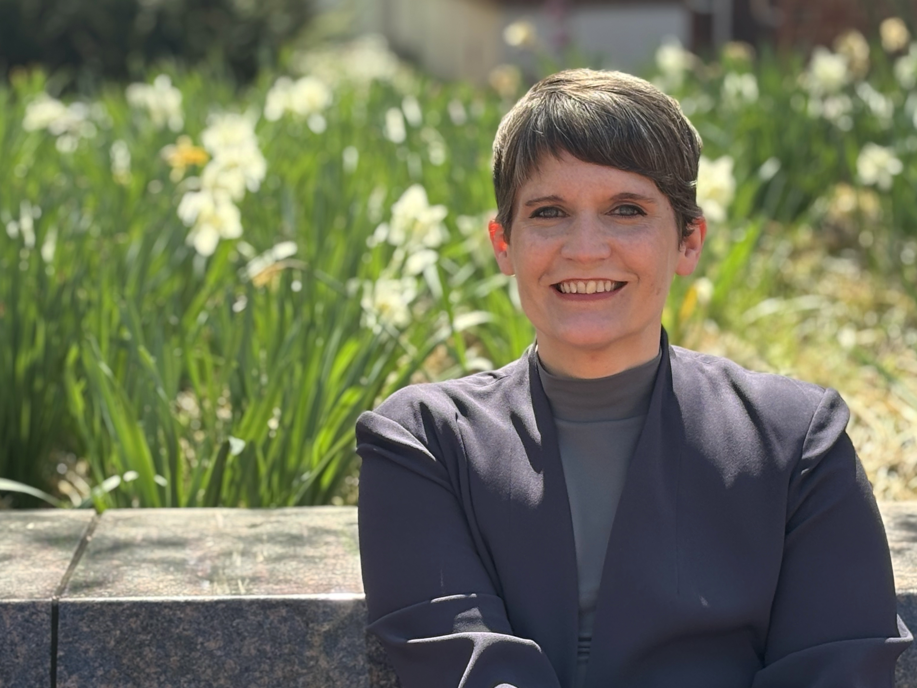 Andrea Miller, Bellisario College professor sitting in front of daffodils on the Penn State campus