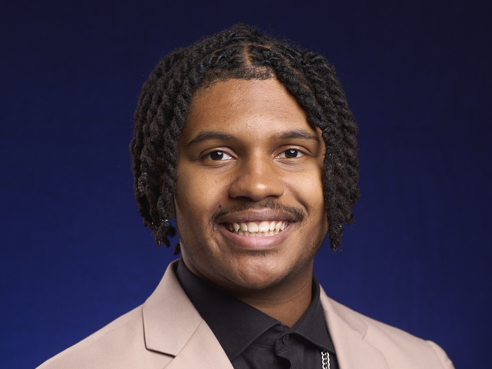 Smiling man with dark hair and a light sport coat