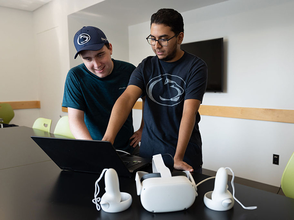 Two students standing and looking at a computer screen in a lab