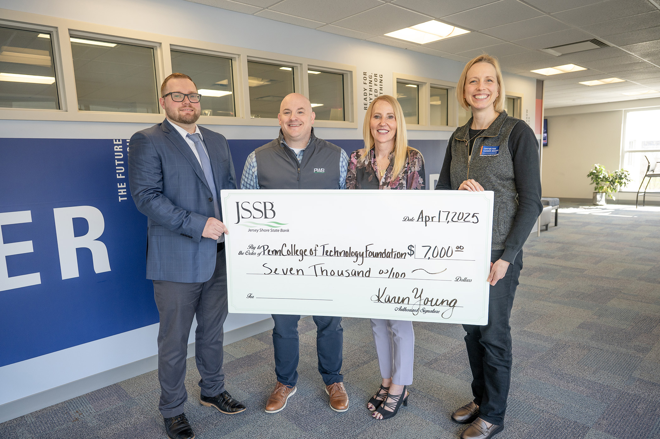 A group of smiling people pose with a big check