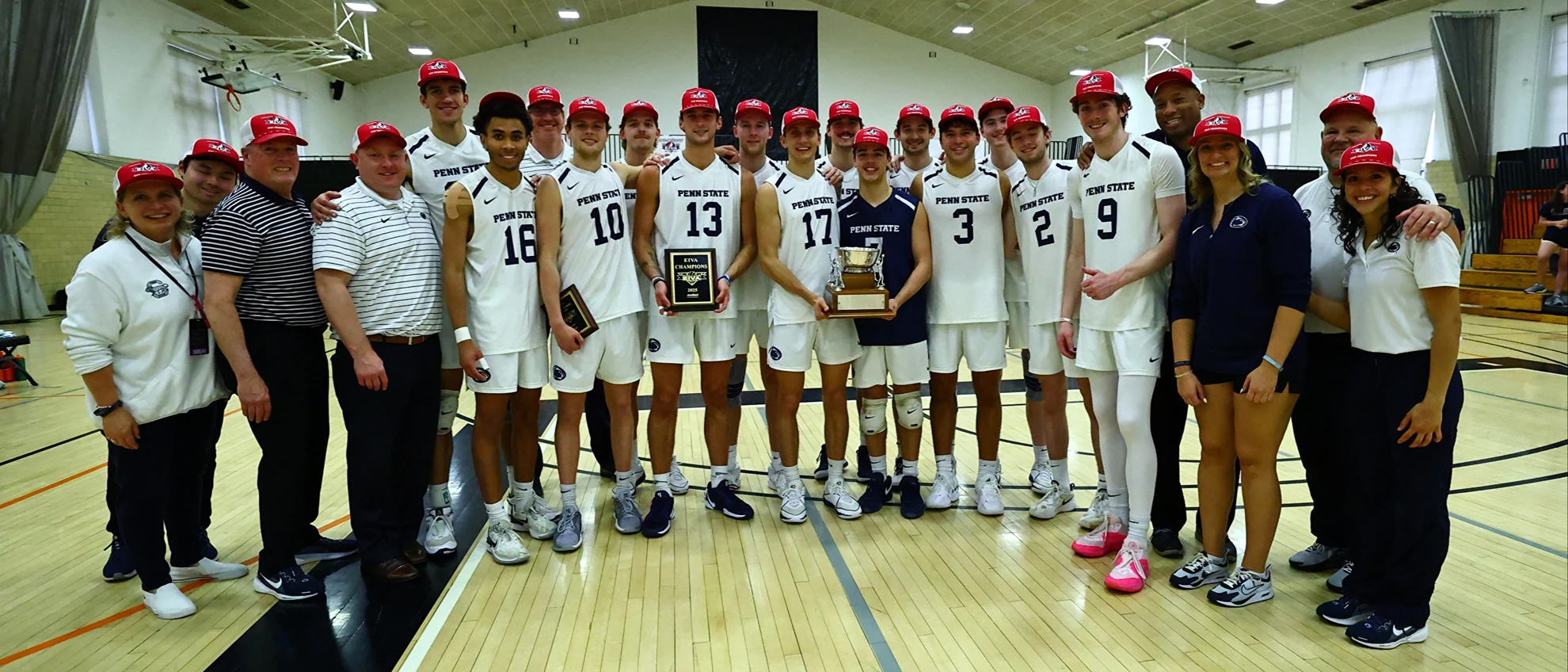 Men's volleyball team poses with trophy