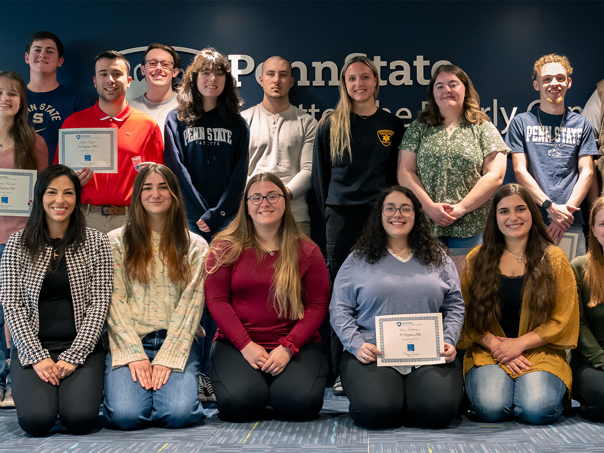 A group of Penn State Fayette students and faculty pose for a photo after an awards ceremony. Several students hold certificates for Pi Sigma Phi honor society.