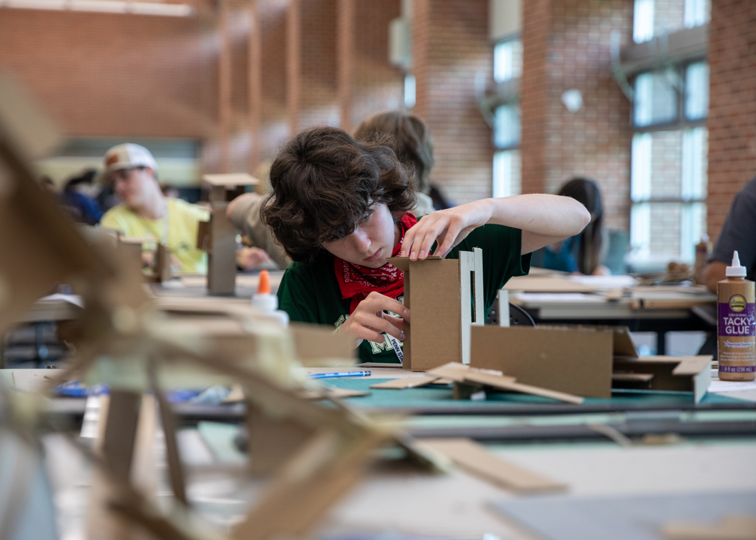 A student building an architectural model out of cardboard.