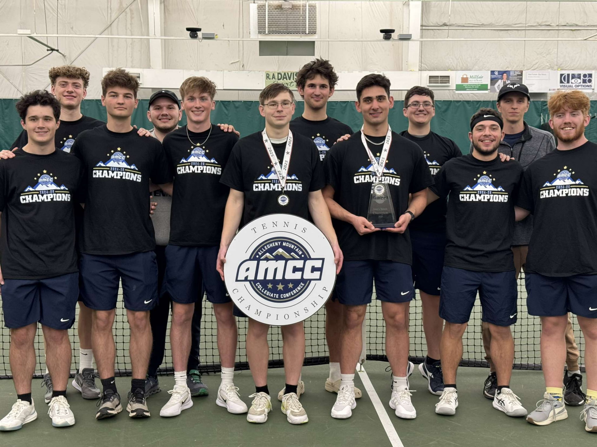 The Penn State Behrend men's tennis team poses with the AMCC championship banner.