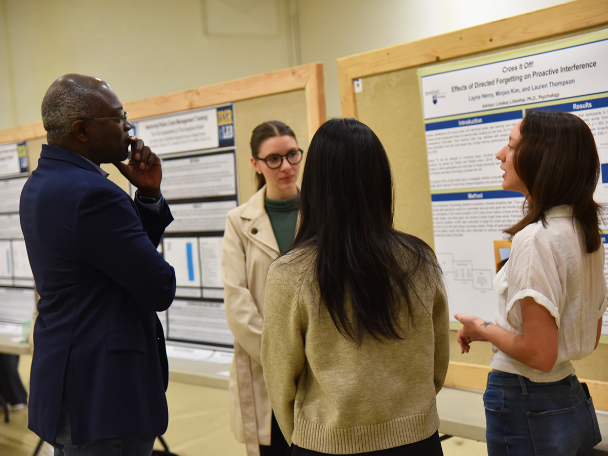 Penn State Altoona Chancellor Ron Darbeau listens to an explanation of research conducted by students Layna Henry, Minjoo Kim and Lauren Thompson.