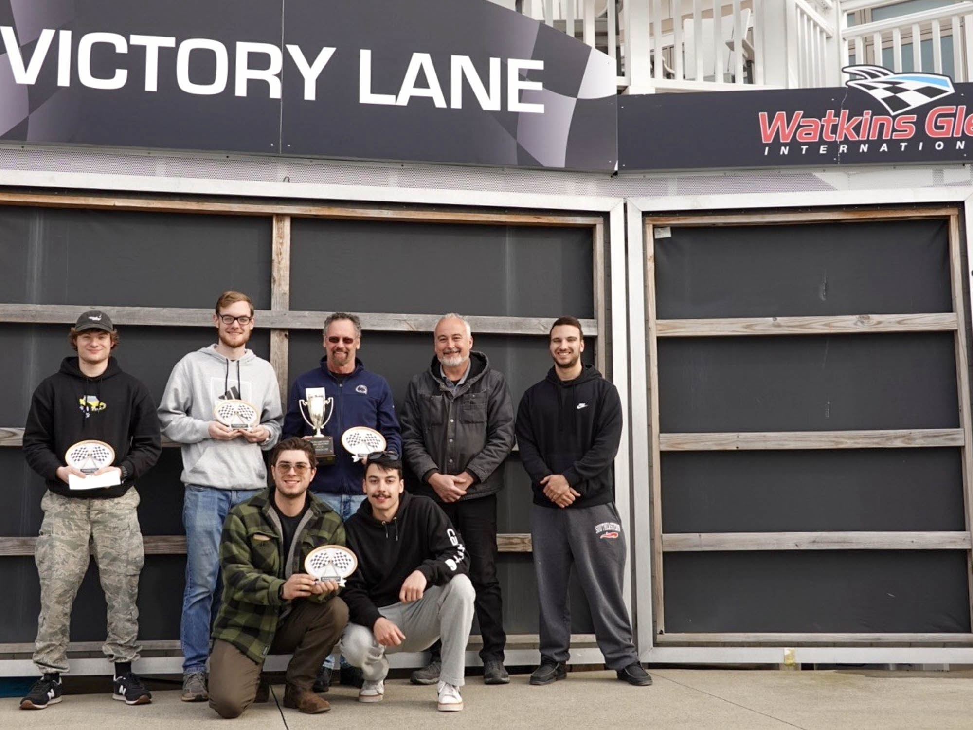 A group of people stand in victory lane at Watkins Glen International