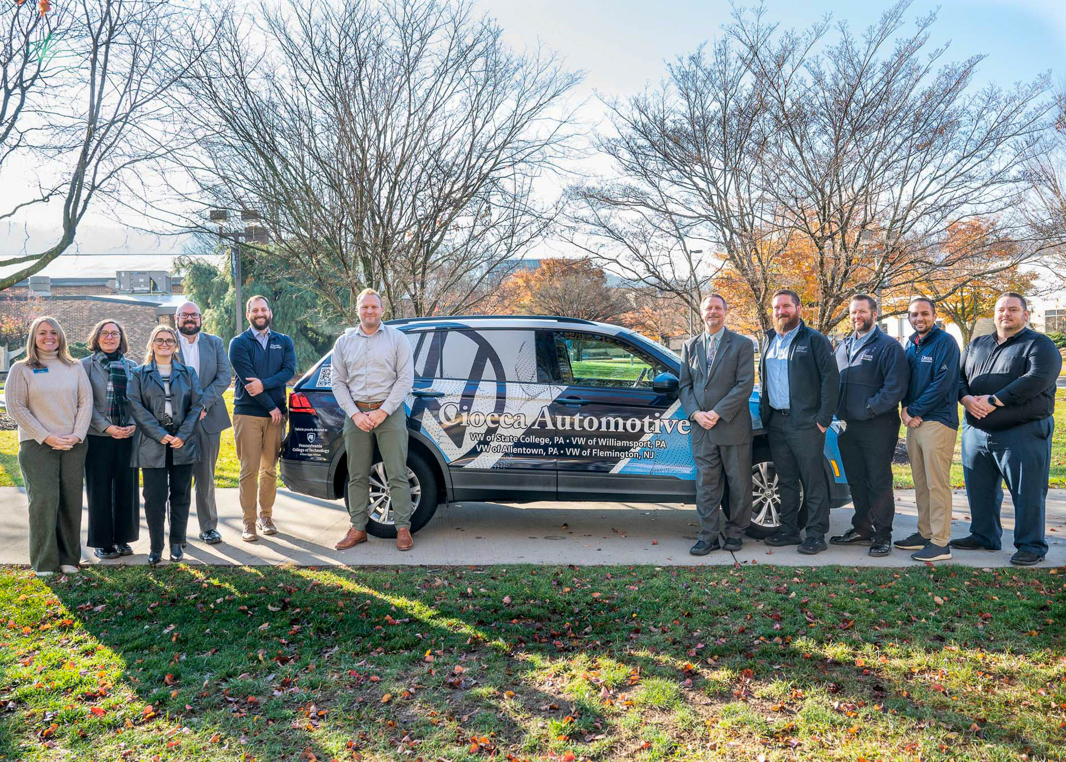 A group of people stand around a car