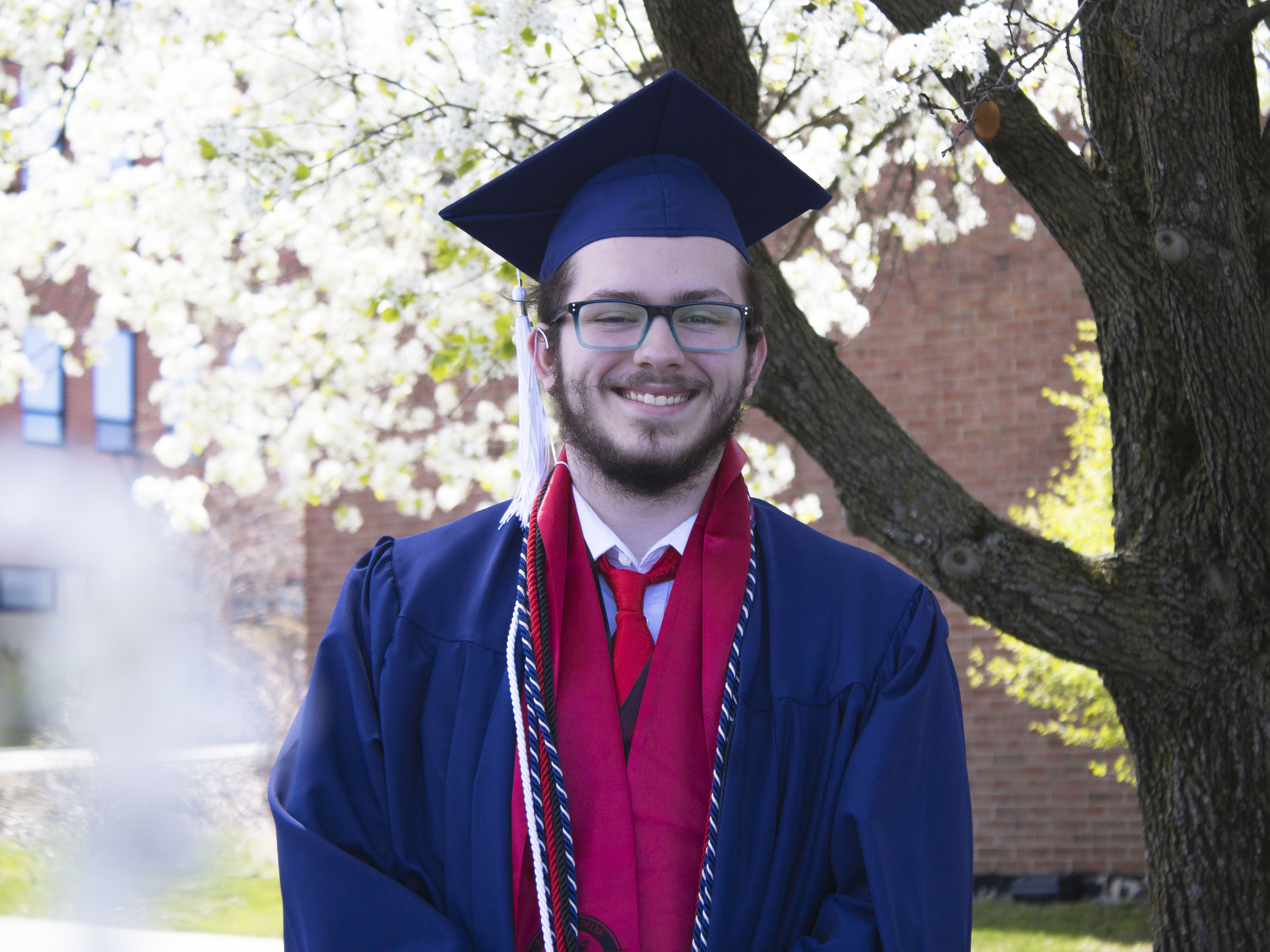 Student wearing commencement regalia and smiling